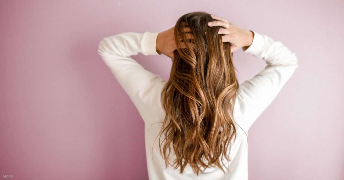 Woman touching her hair after hair restoration treatment with CENTRIcyte