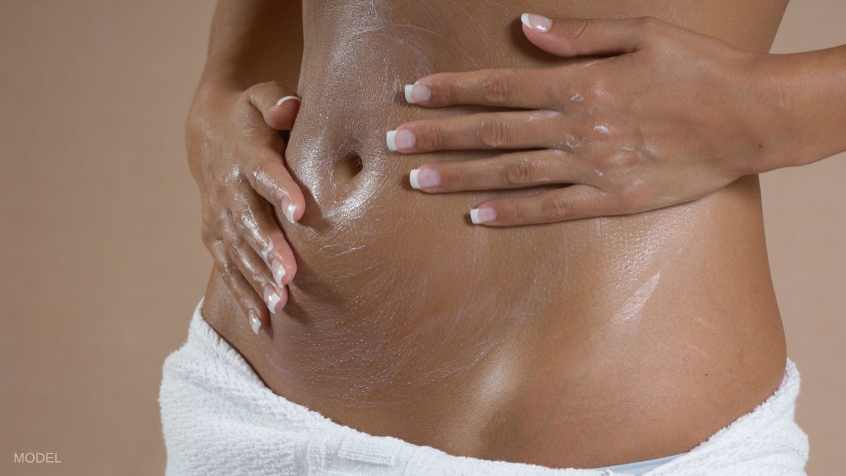 Woman with hands on bare stomach and towel around her waist. (MODEL)