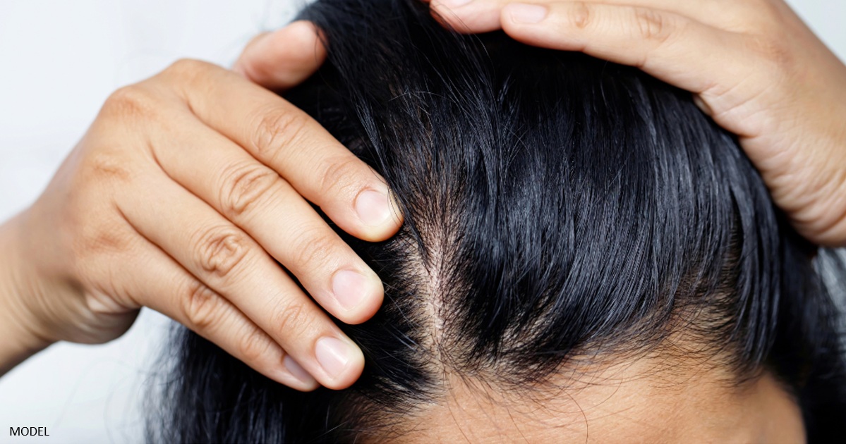 Woman experiencing thinning hair looking at her scalp