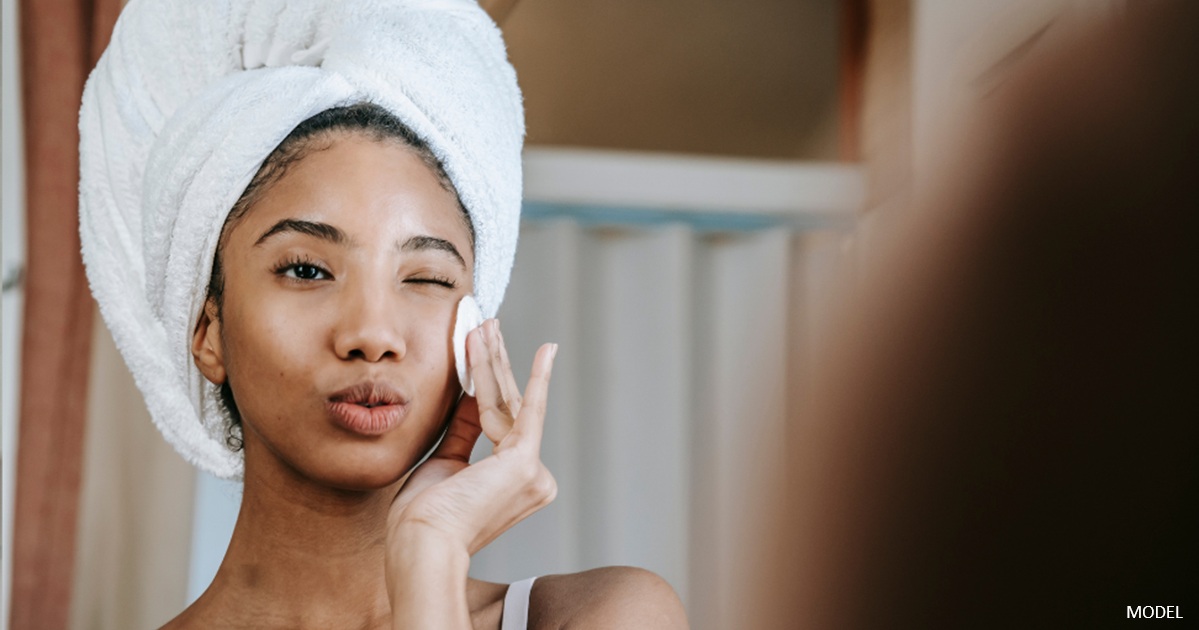 Young woman looking in the mirror during a skincare routine
